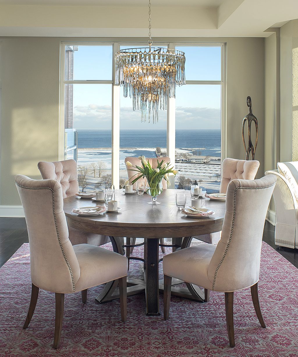Pastel pink velvet chairs soften the brighter pink rug in this coastal dining room.